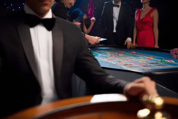 A professional dealer in a tuxedo greeting players at the roulette table, symbolizing the authentic live casino feel at BDKO.