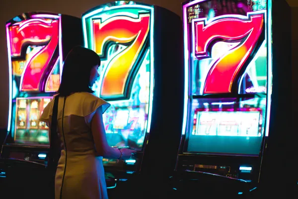 A woman smiling while playing online games on her laptop, surrounded by neon casino elements, showcasing BDKO’s diverse game collection.