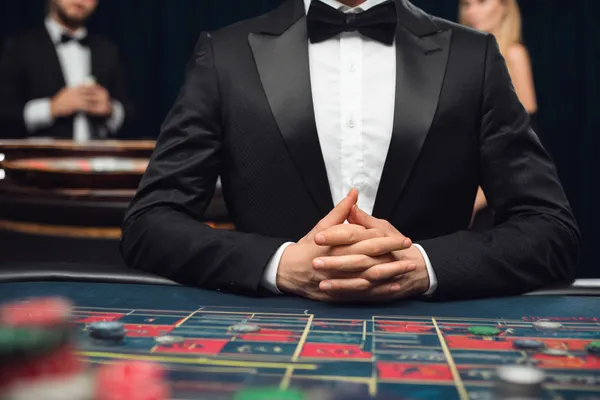 A woman in a luxurious green gown next to an ornate roulette wheel, capturing the upscale casino mood of BDKO.